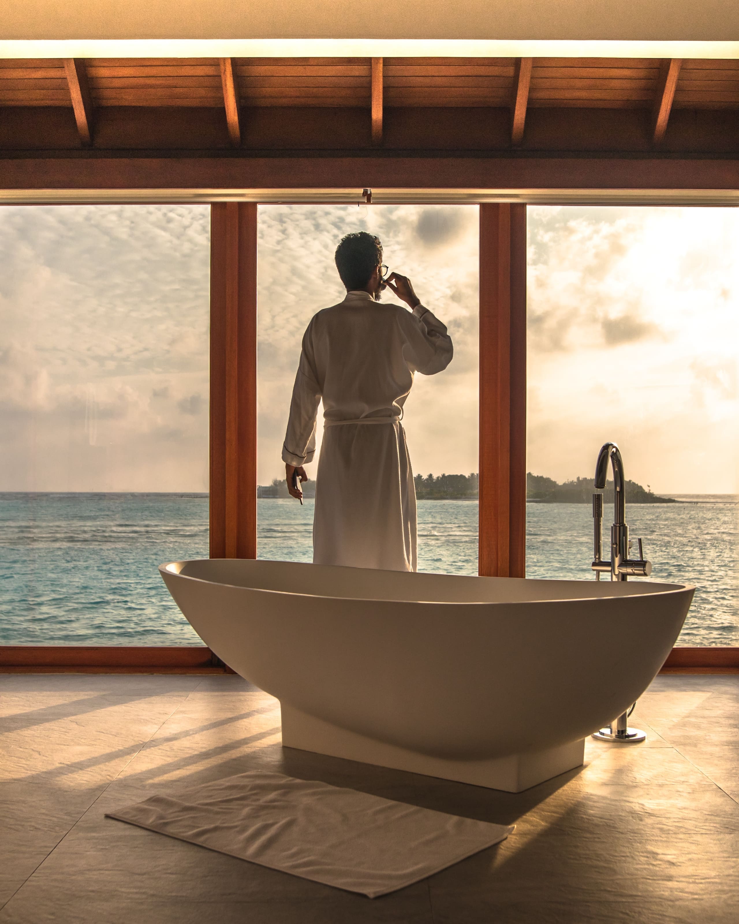 Guest enjoying coffee at sunrise in an overwater suite