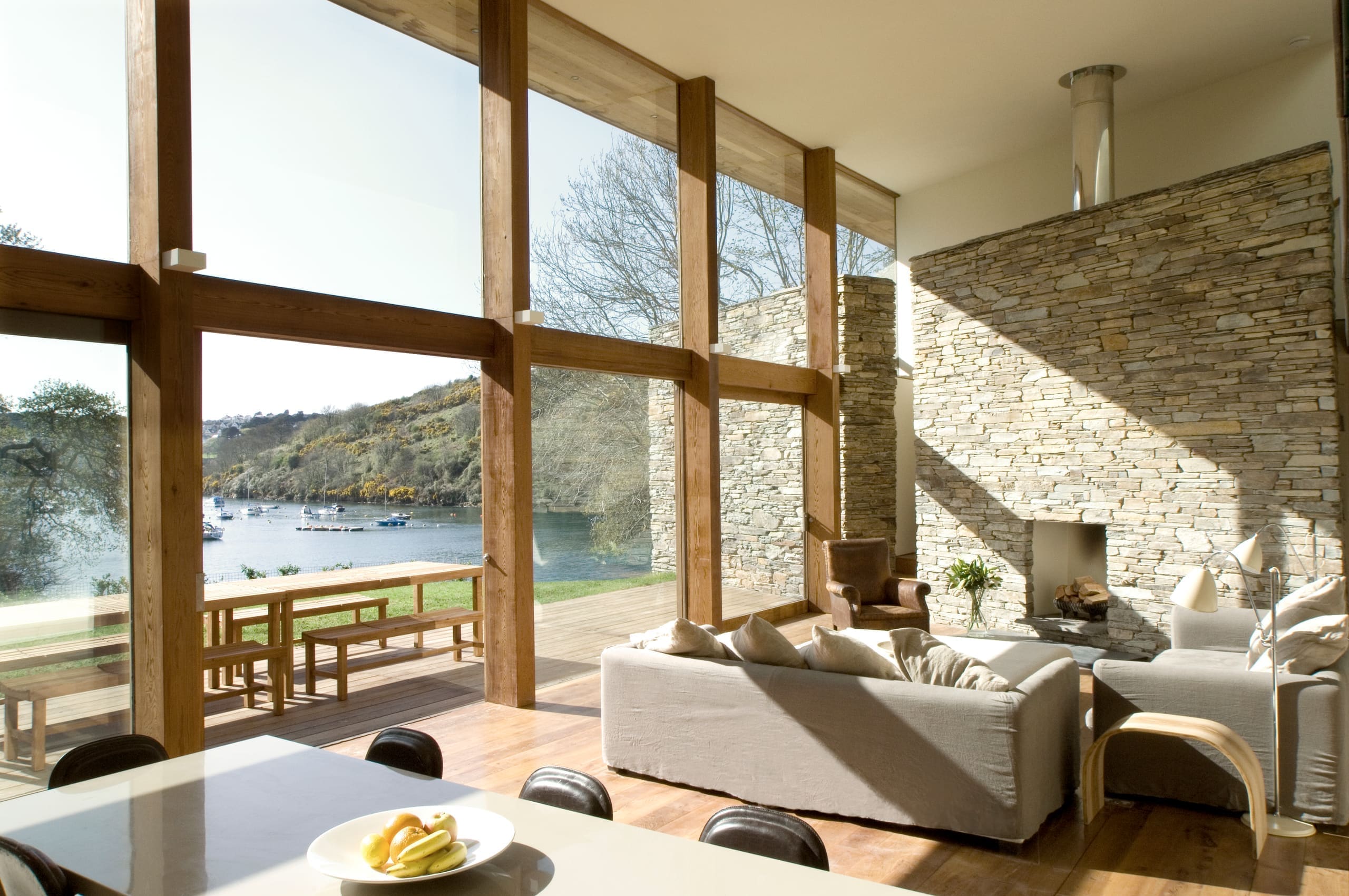 Waterfront living room with floor-to-ceiling windows overlooking moored boats
