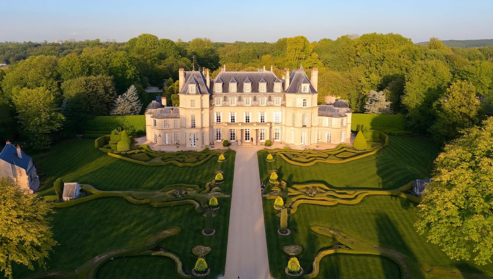 Aerial view of a luxurious château-like estate home with expansive manicured gardens